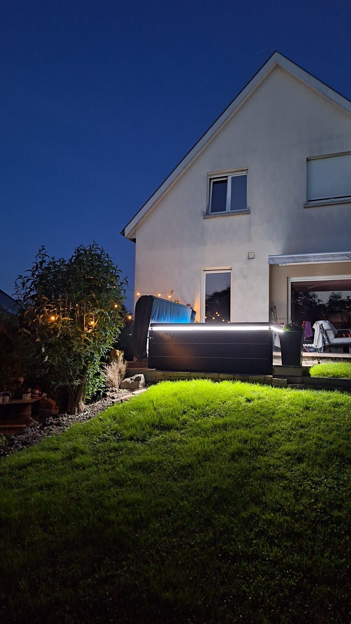 Une maison blanche avec un jacuzzi devant elle la nuit.
