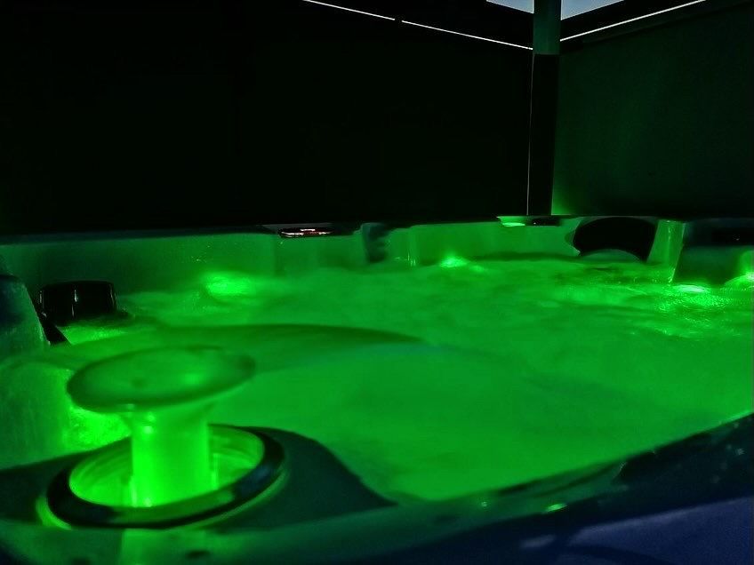 Un bain à remous est éclairé par des lumières vertes la nuit.