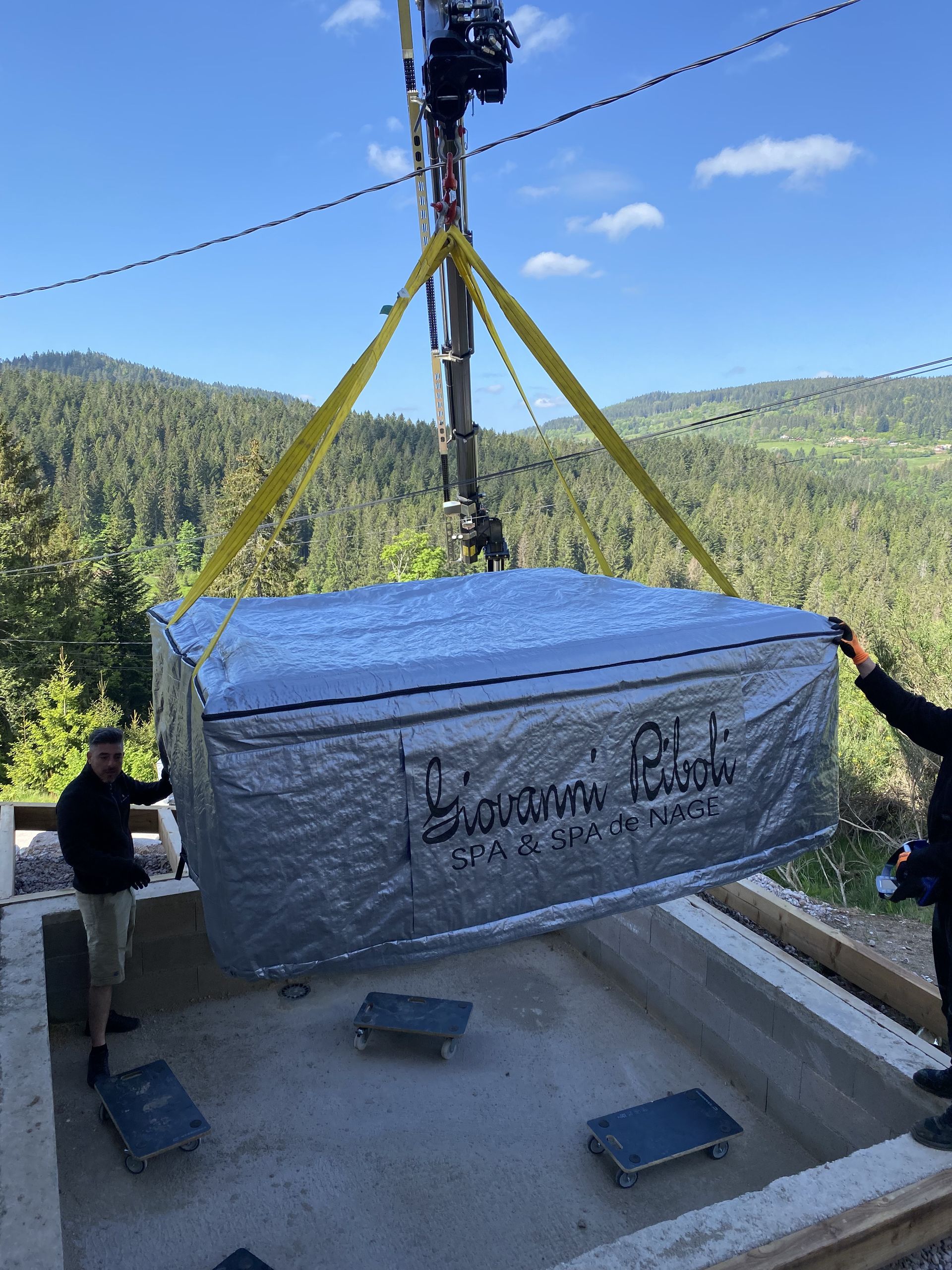 Un homme soulève un grand conteneur avec une grue en arrière-plan.