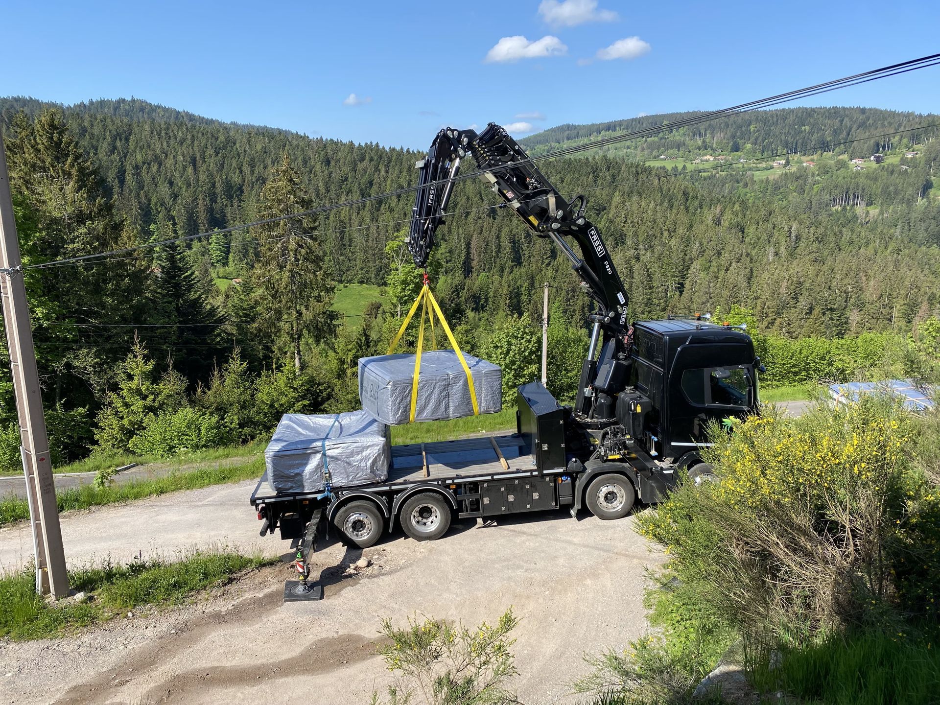 Un camion est soulevé par une grue sur un chemin de terre.