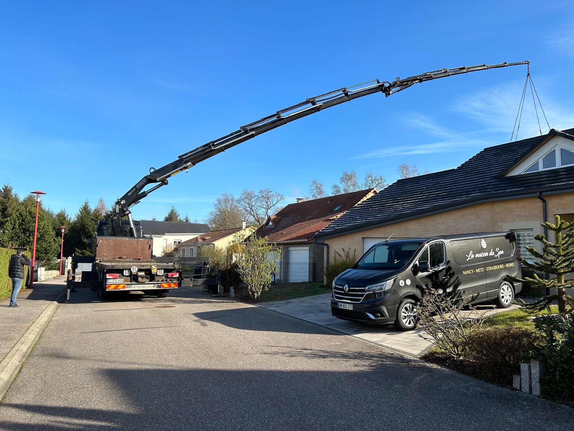 Un camion avec une grue attachée est garé devant une maison.
