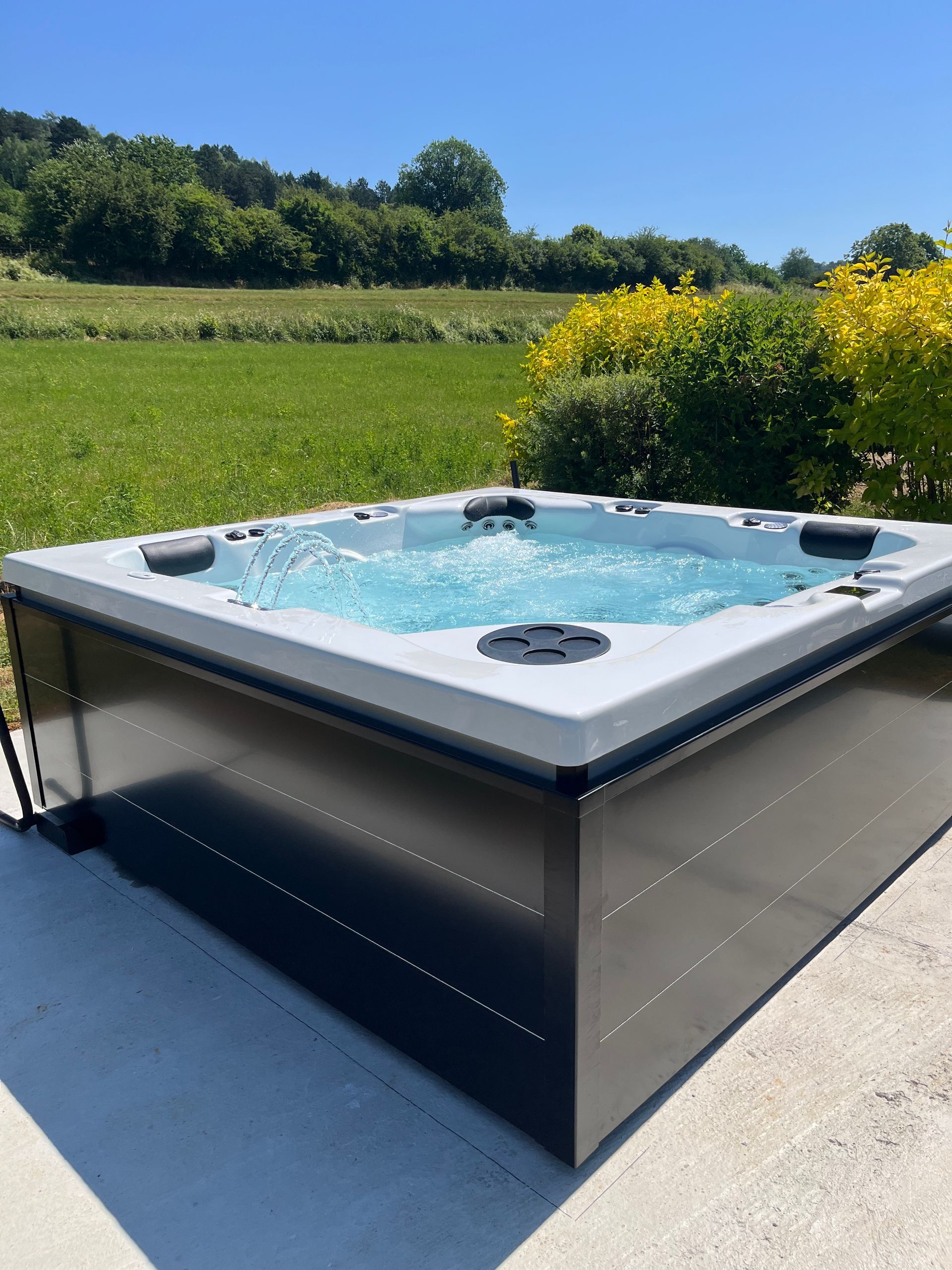 Un bain à remous est installé sur une terrasse devant un champ.