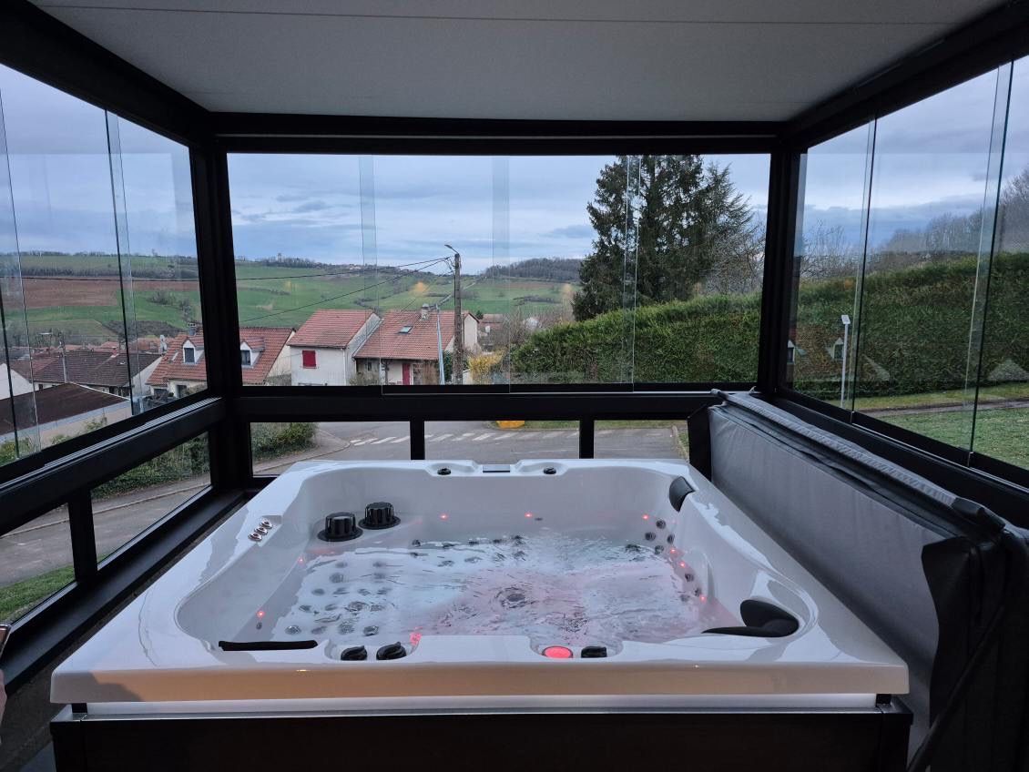 Un bain à remous est installé sur un balcon avec vue sur la campagne.