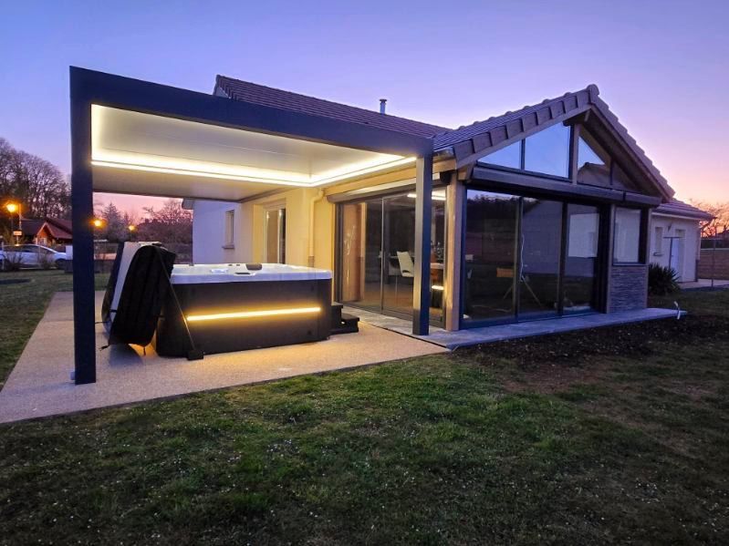 Une maison avec un jacuzzi sous une pergola dans l'arrière-cour.