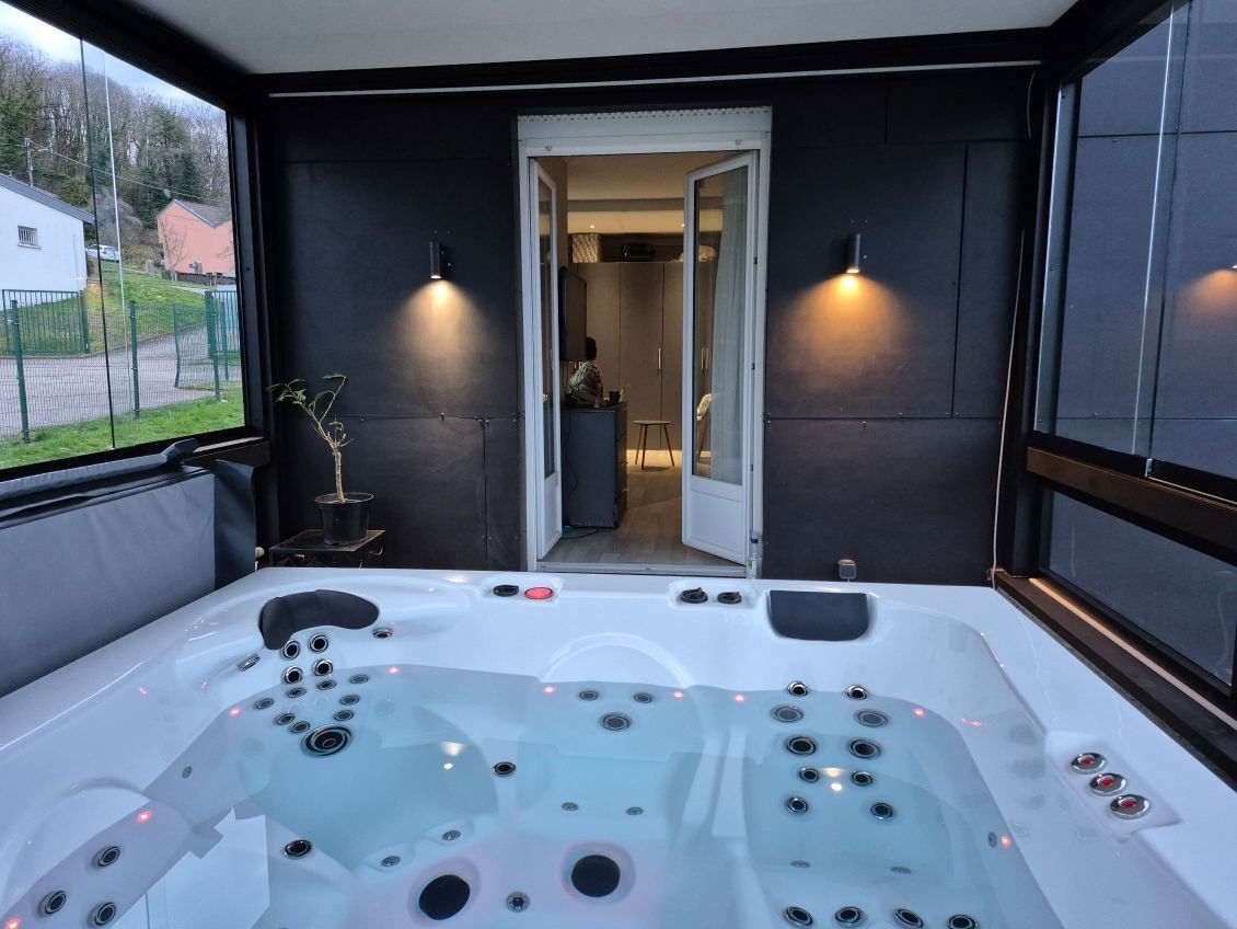 Un bain à remous est assis sur un porche avec une porte ouverte