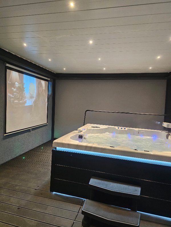 Un bain à remous est installé dans une pièce à côté d'un écran de projection.