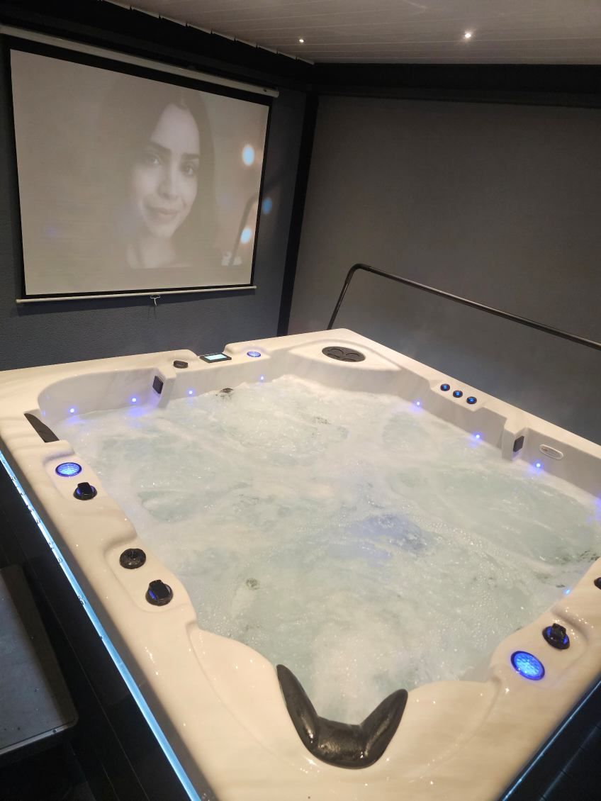Un grand bain à remous avec un écran de projection derrière