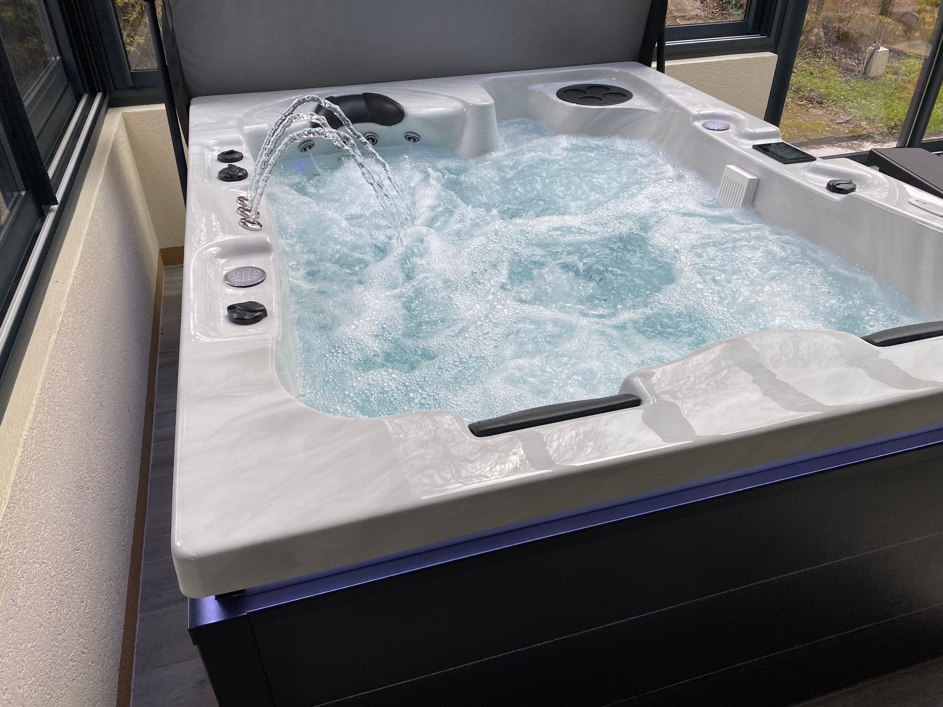 Un grand bain à remous blanc rempli d'eau bleue est posé sur un balcon.