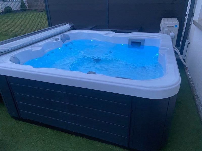 Un bain à remous rempli d'eau bleue est posé sur une pelouse verte luxuriante.