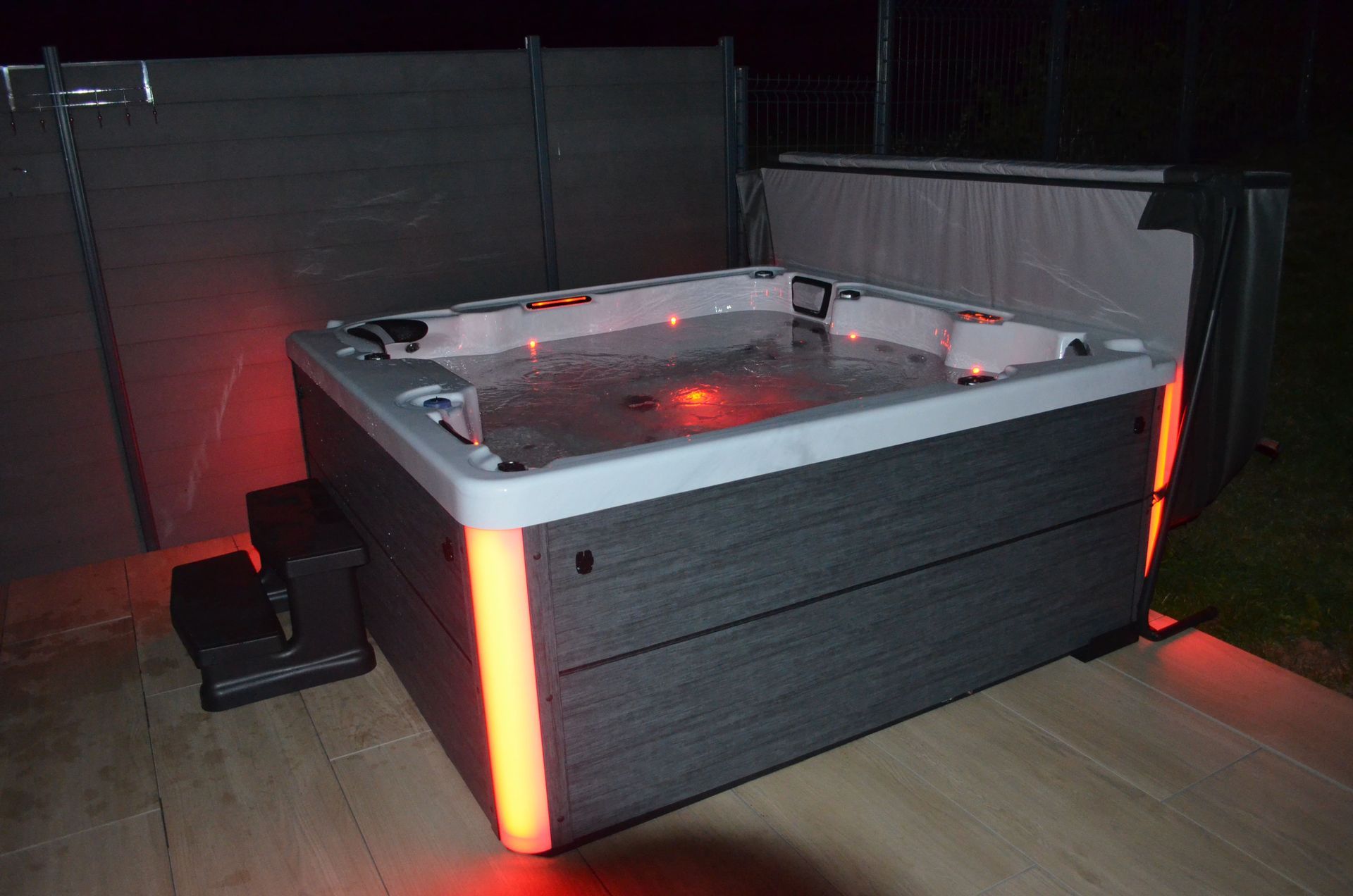 Un bain à remous est éclairé la nuit et assis sur une terrasse.