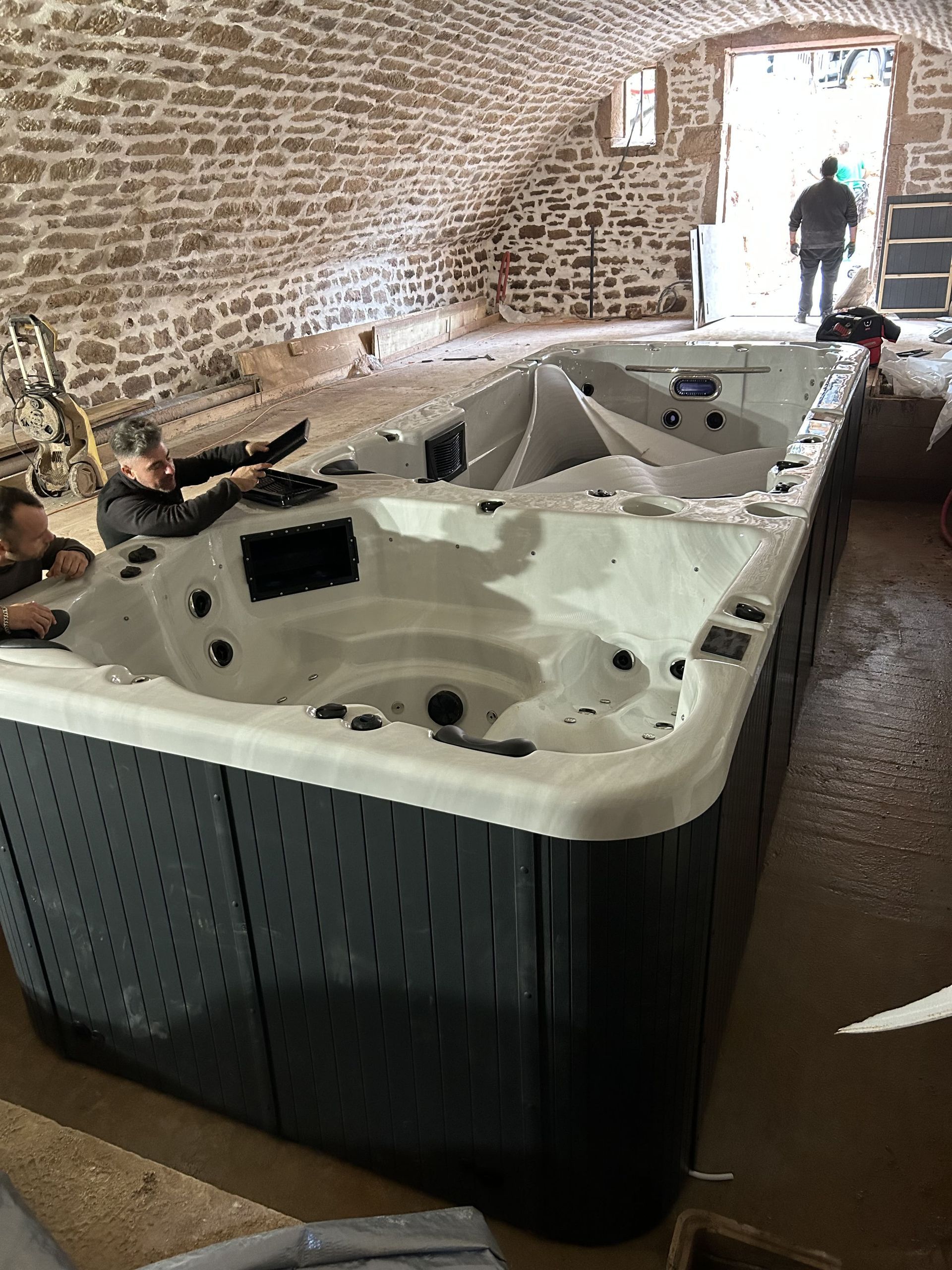 Un grand bain à remous est installé dans une pièce à côté d'un mur de briques.