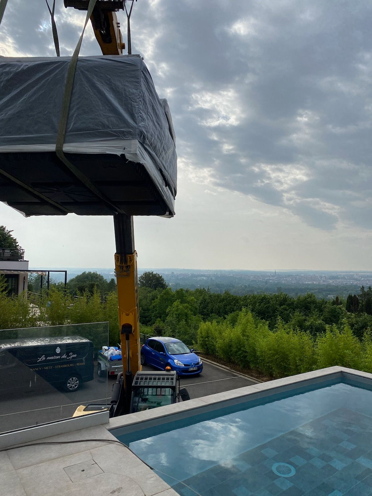 Une grue soulève un gros objet au-dessus d'une piscine.