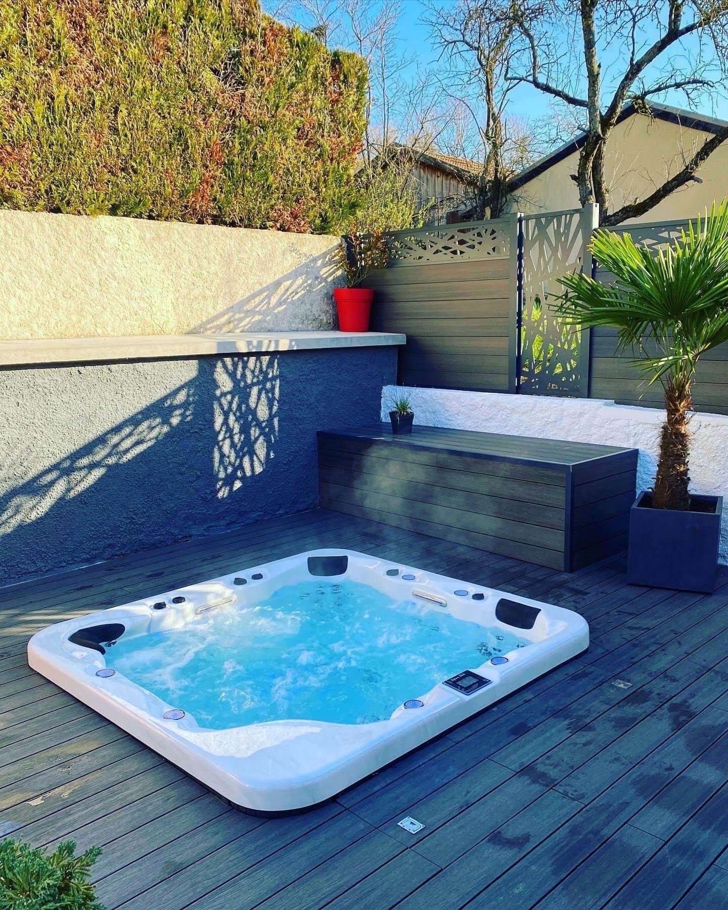 Un bain à remous est posé sur une terrasse en bois.