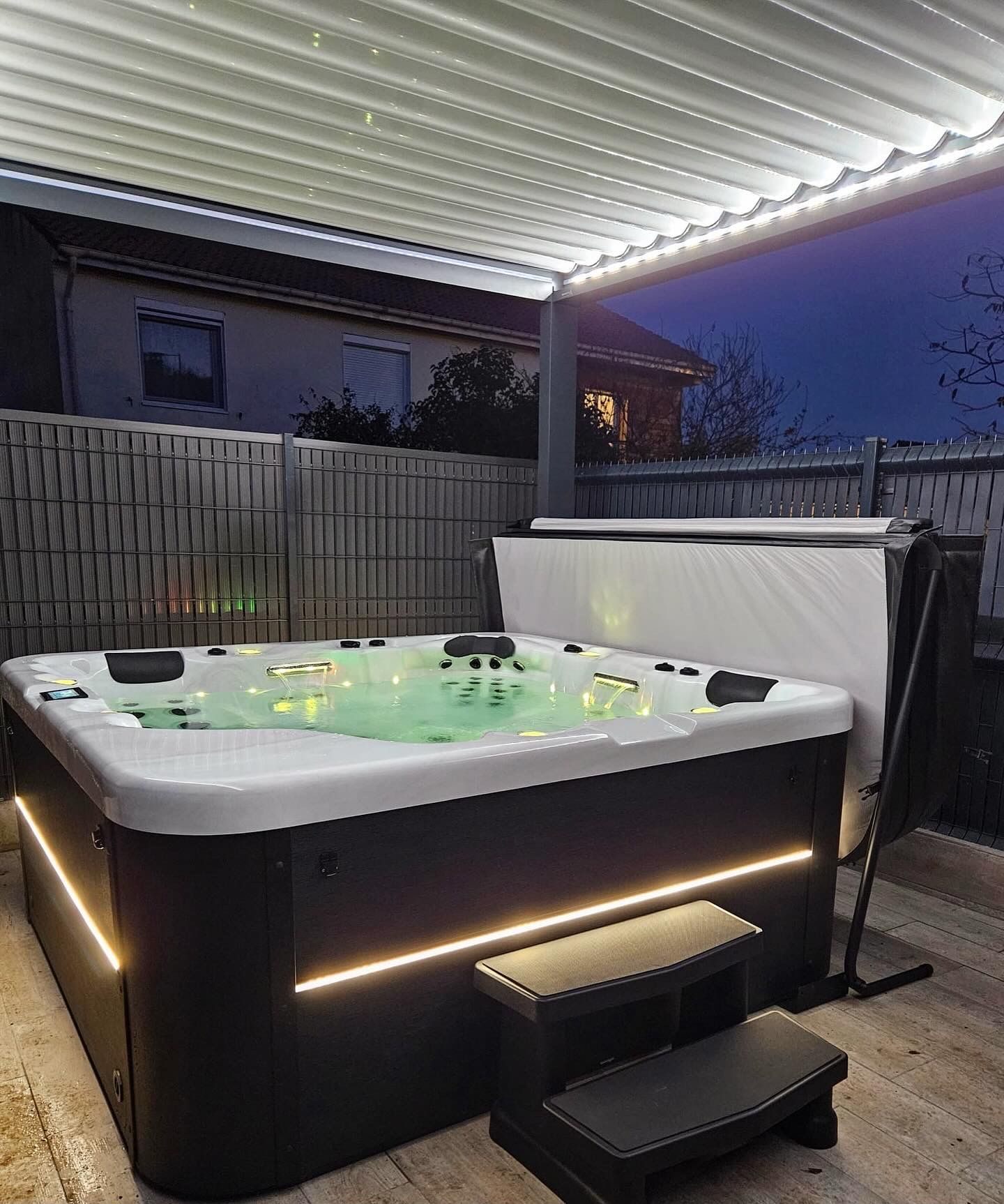 Un jacuzzi est installé sous une pergola la nuit.