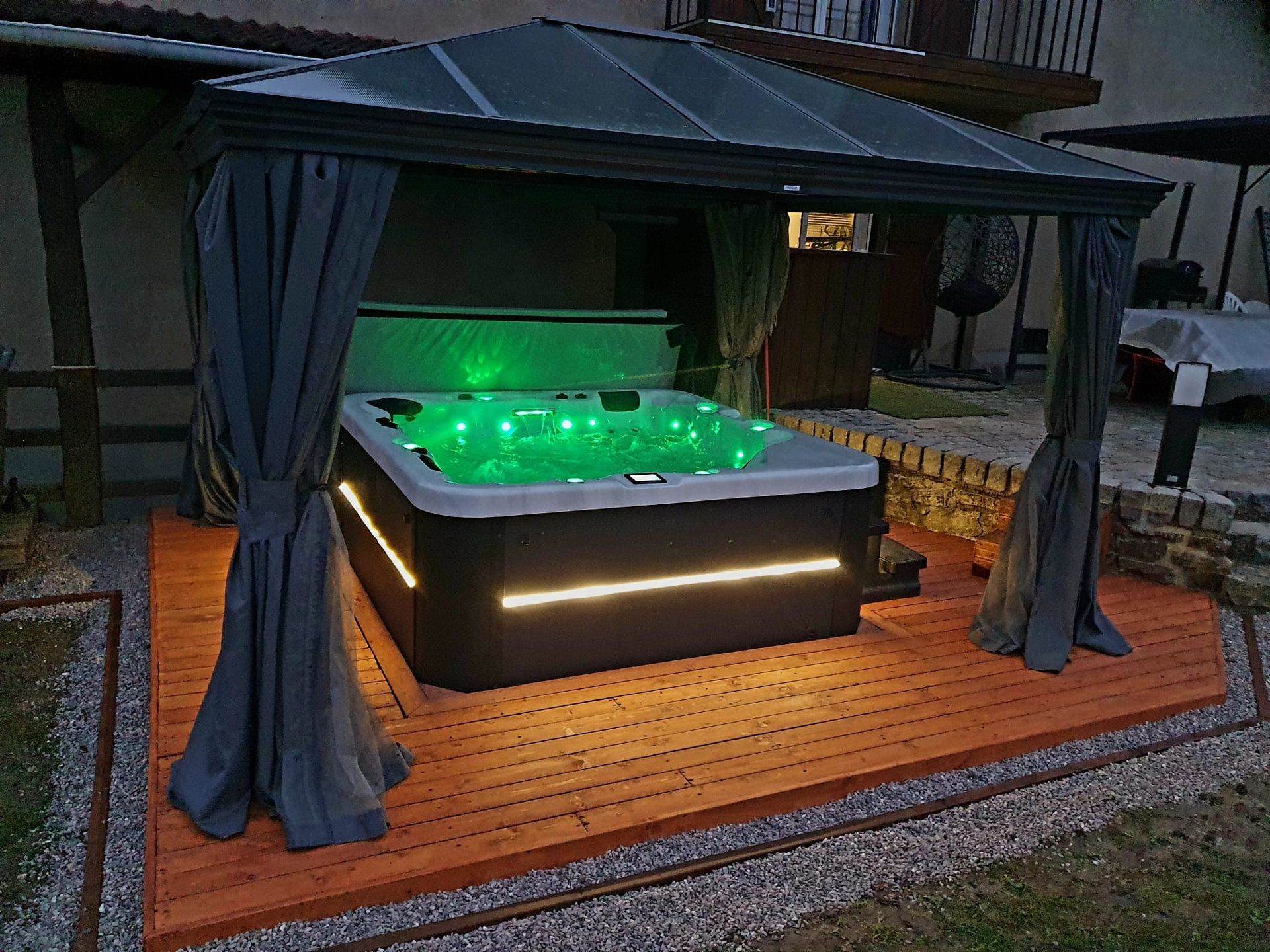 Un bain à remous est installé sous un belvédère avec des lumières vertes dessus.