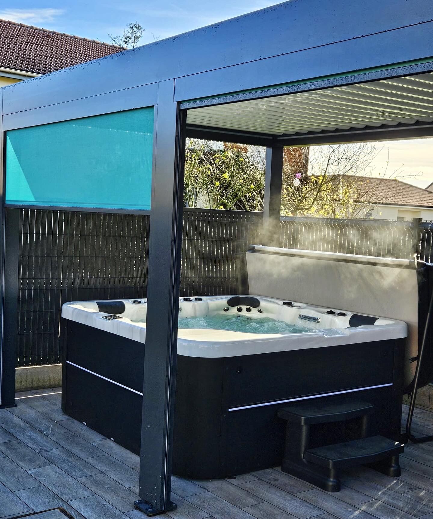 Un jacuzzi noir et blanc se trouve sous une pergola.
