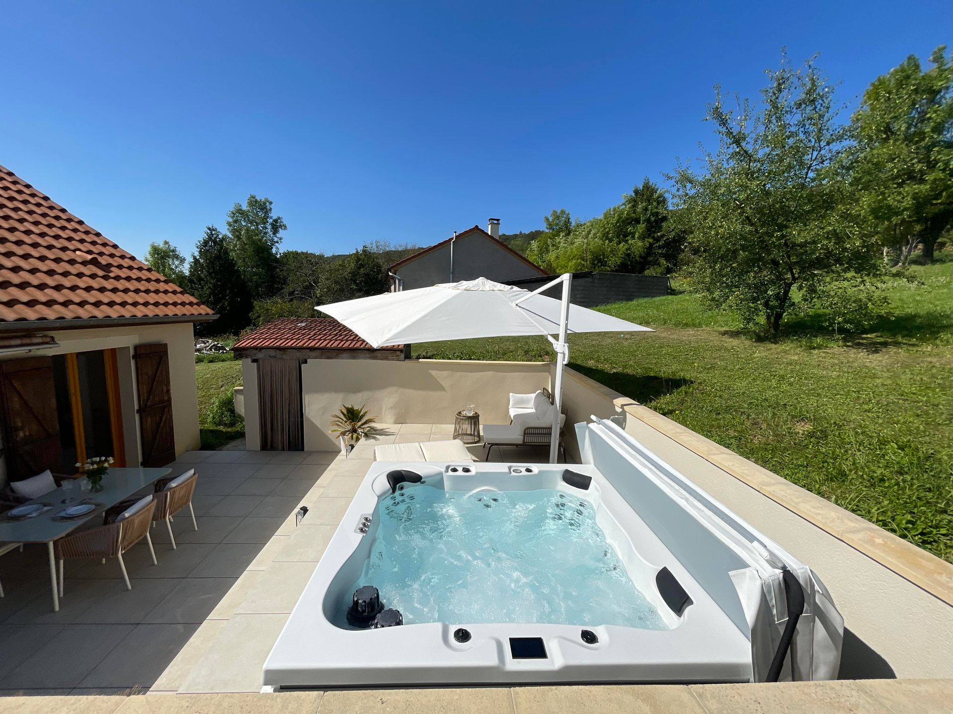 Un bain à remous est installé sur une terrasse à côté d'une maison.