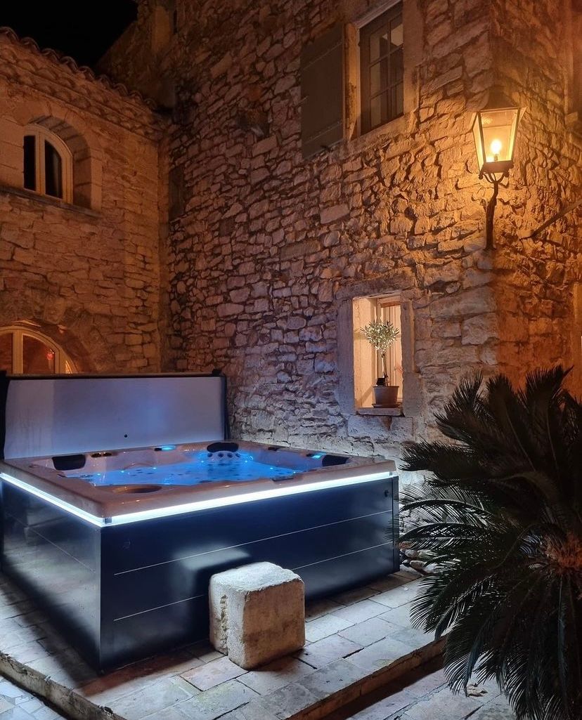 Un jacuzzi devant un bâtiment en pierre la nuit