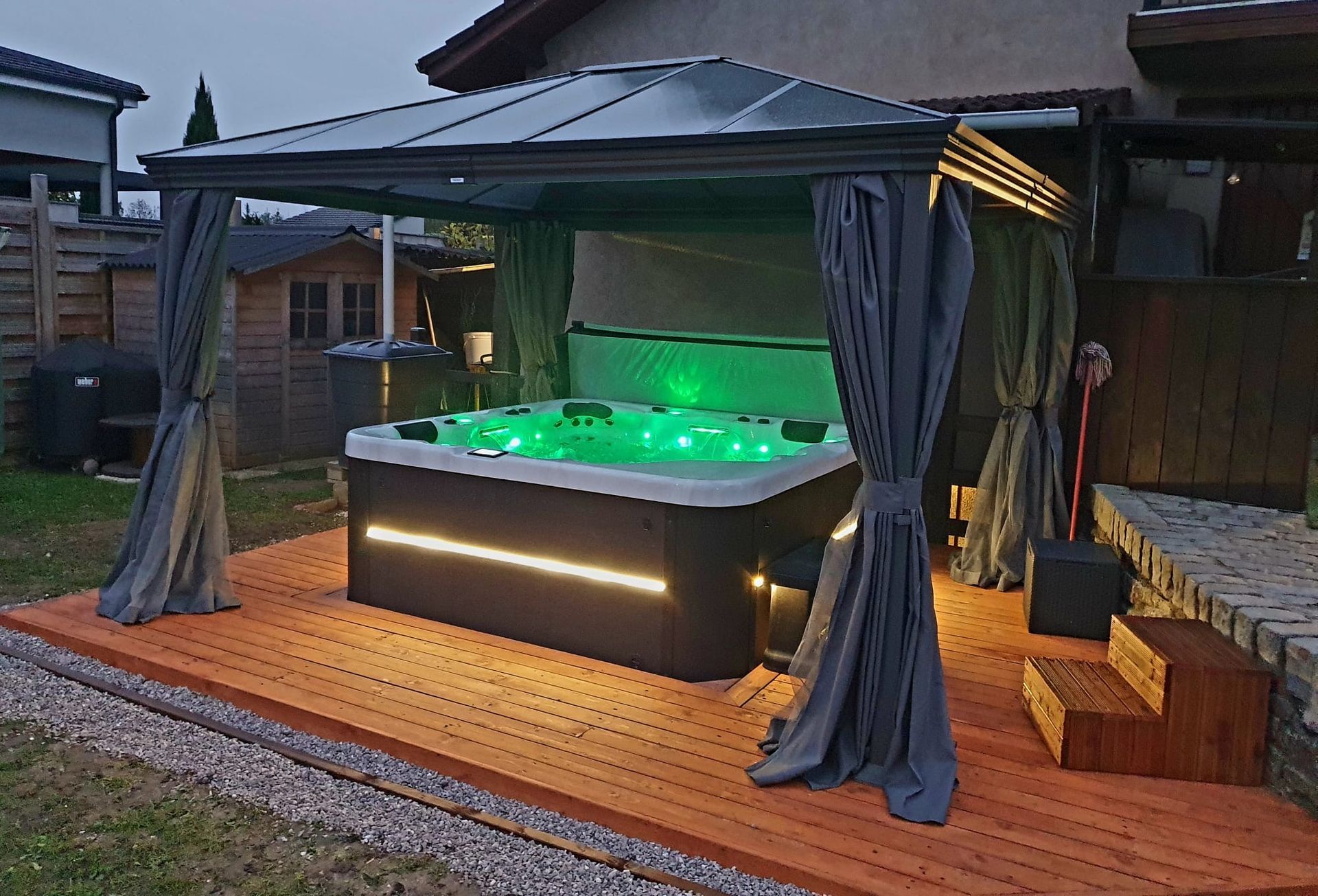 Un jacuzzi sous un gazebo avec des lumières vertes dessus