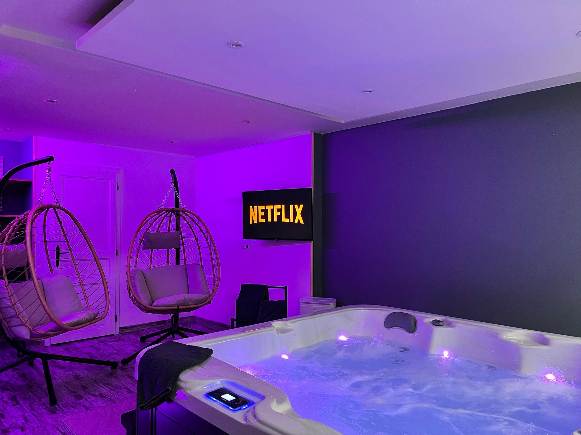 Un salon avec un jacuzzi et un panneau Netflix sur le mur.