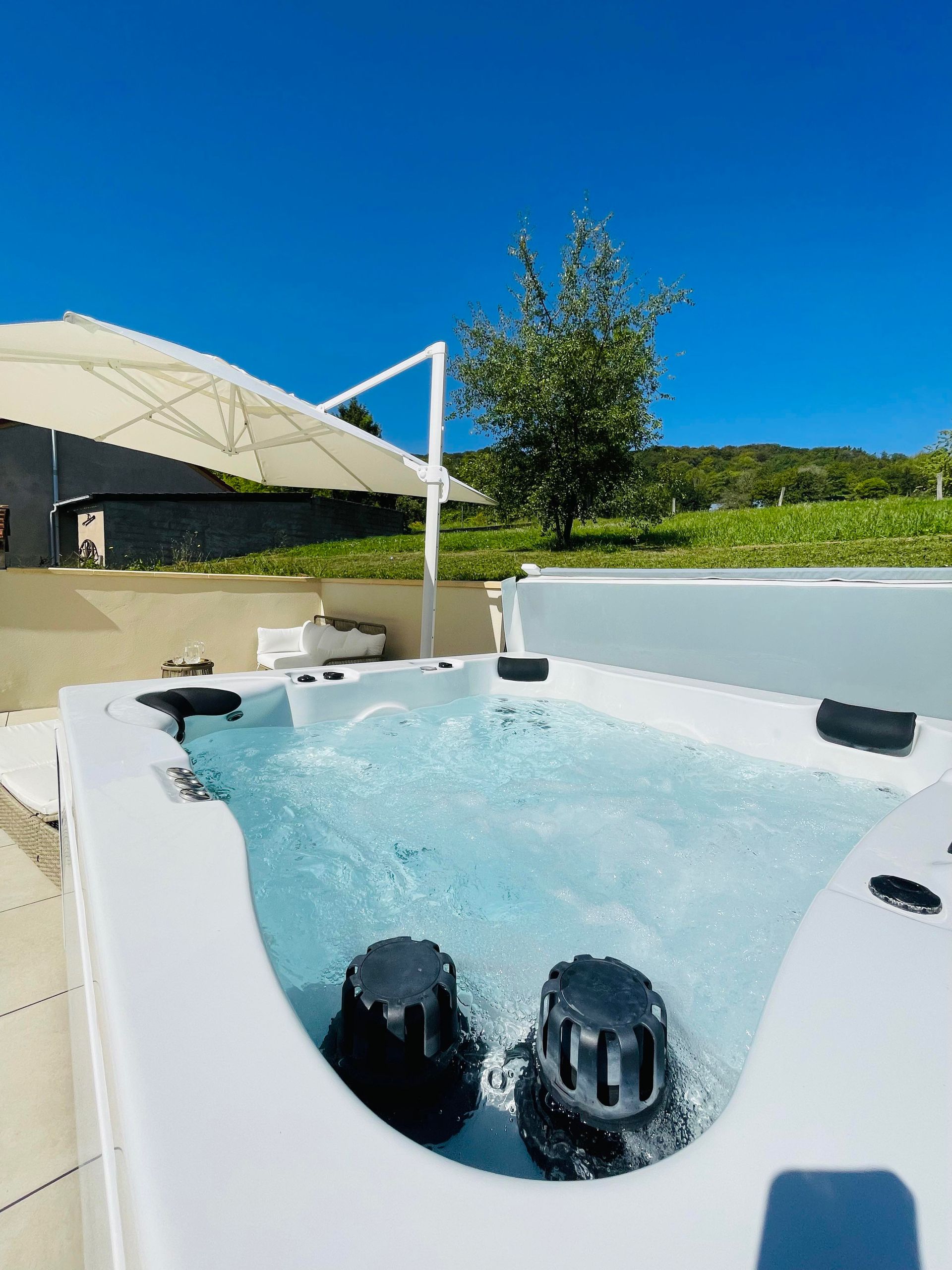 Un jacuzzi blanc avec un parasol blanc en arrière-plan.
