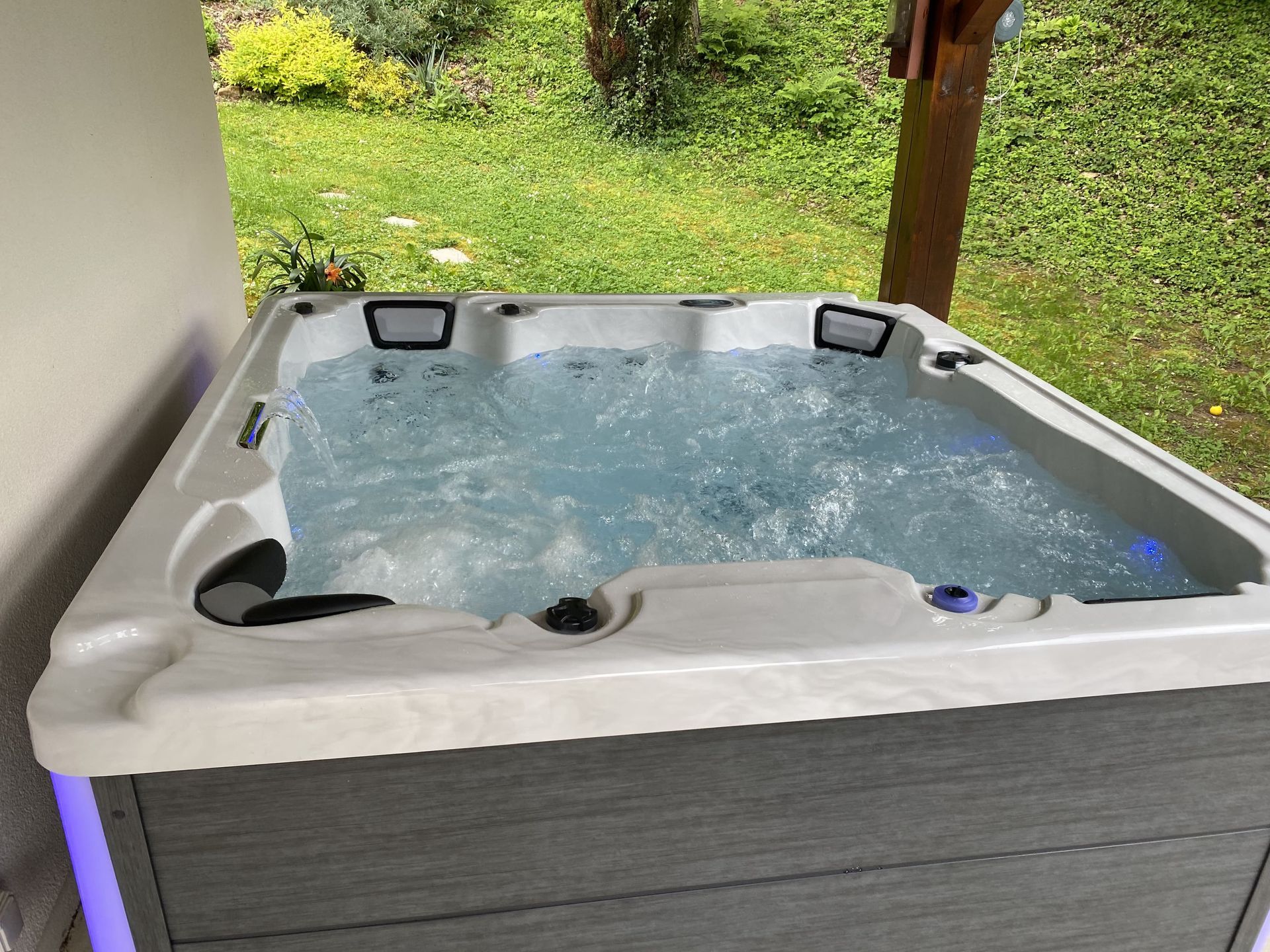 Un jacuzzi blanc et gris est rempli d'eau bleue.