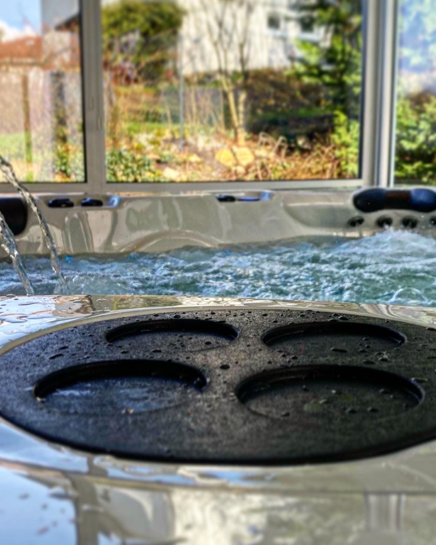 Un jacuzzi avec de l'eau qui en sort et une fenêtre en arrière-plan.