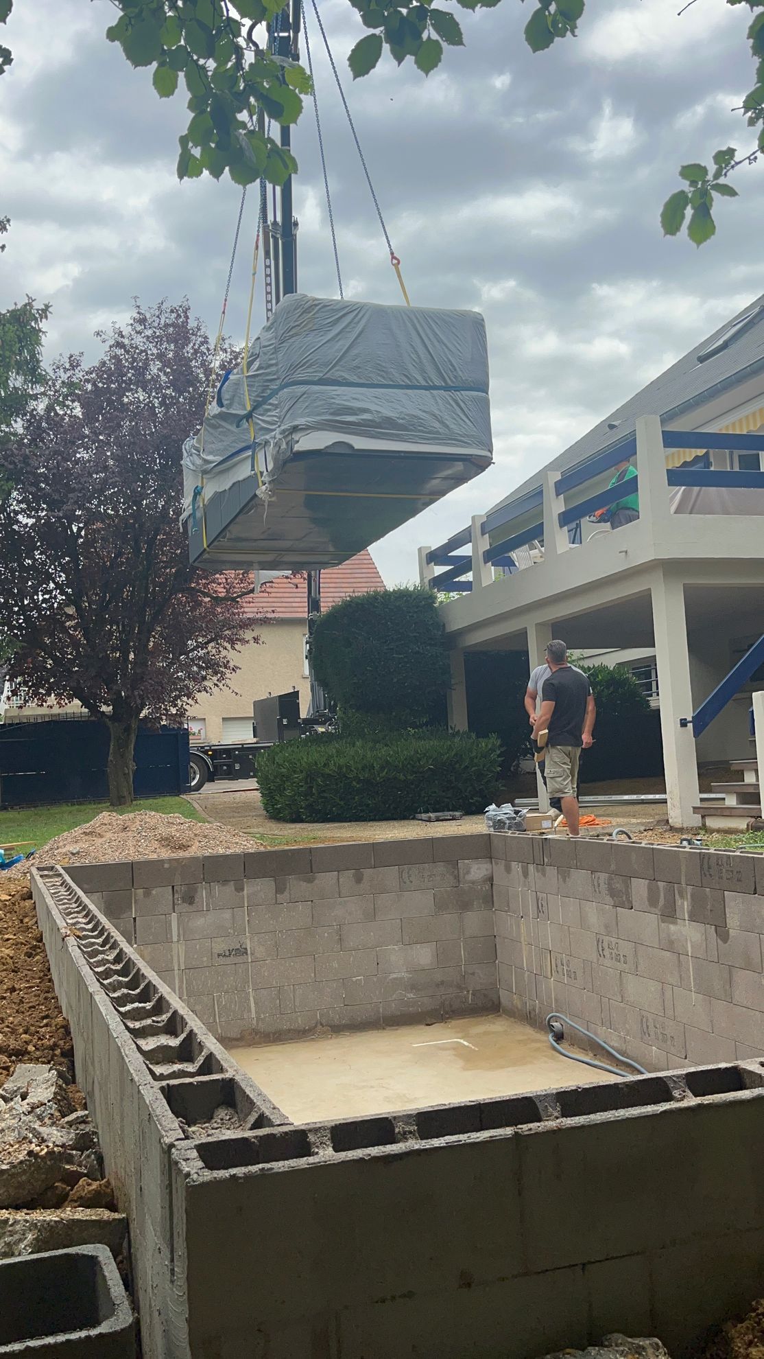 Une grue soulève un gros morceau de métal dans une piscine.