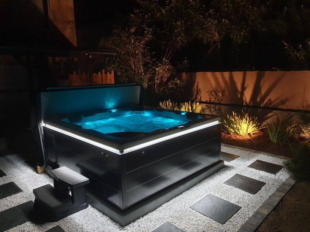 Un jacuzzi est éclairé la nuit dans une cour arrière