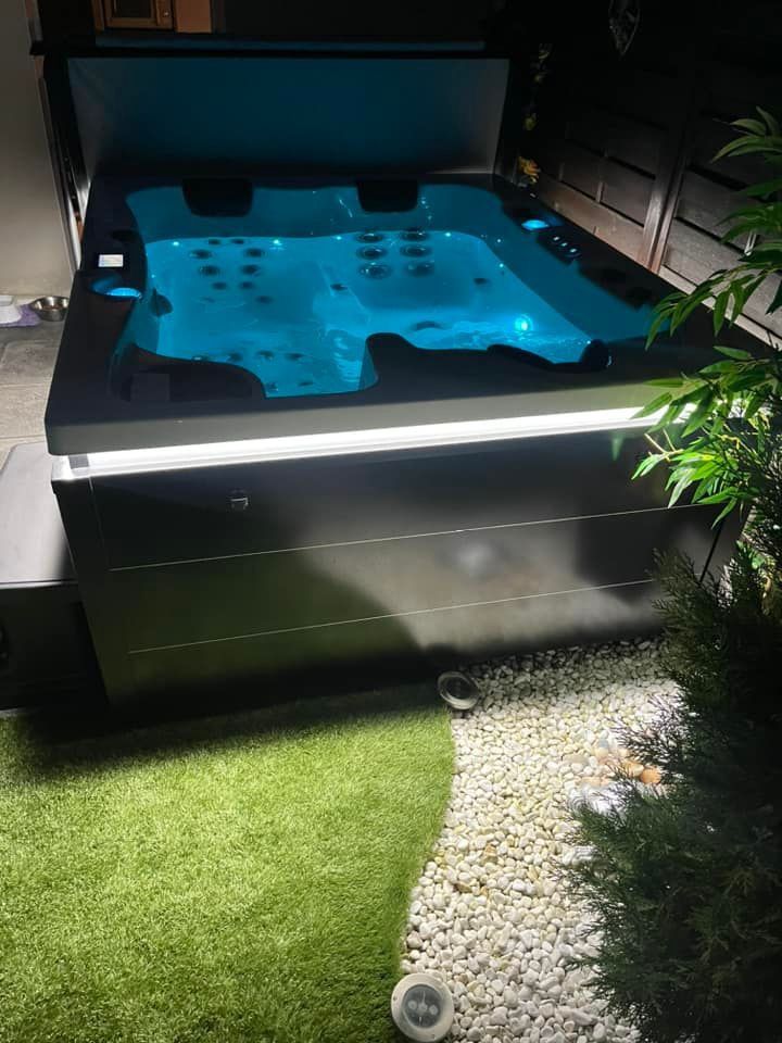 Un bain à remous est éclairé la nuit dans une cour arrière.