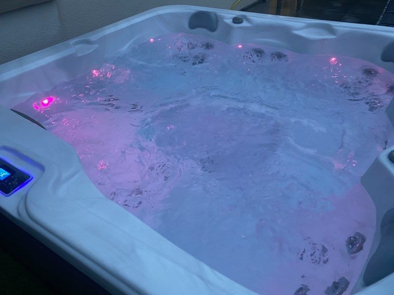 Un bain à remous avec des lumières violettes dessus est rempli d'eau.
