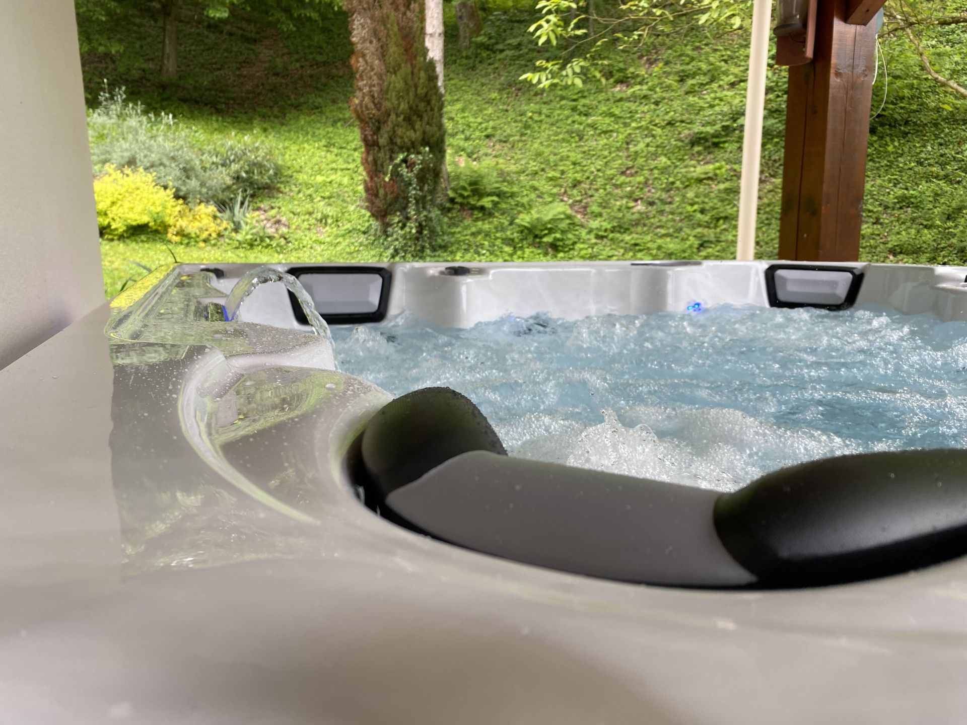 Un bain à remous est assis sur un porche avec des arbres en arrière-plan.