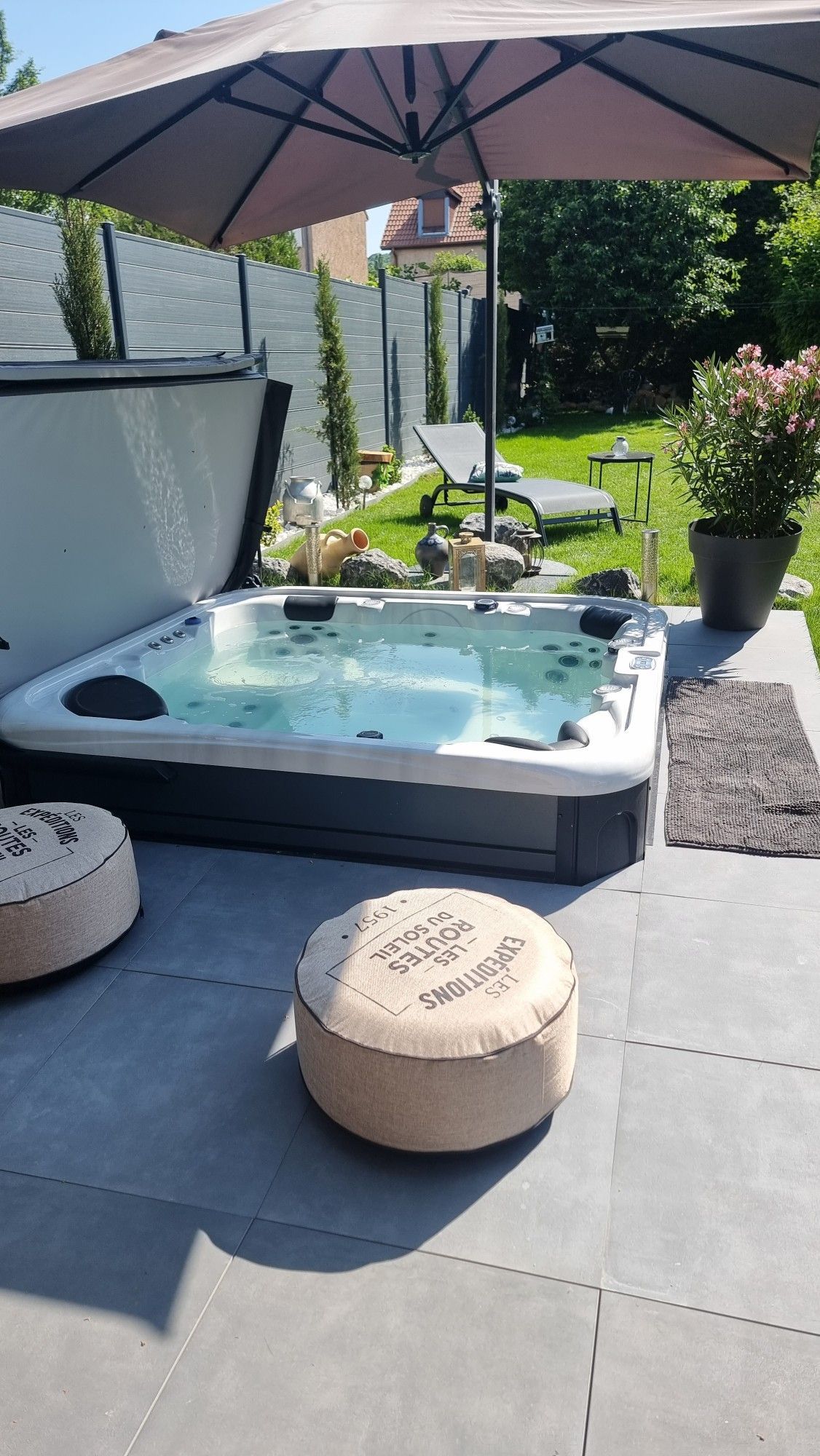 Un bain à remous est installé sous un parasol sur une terrasse.