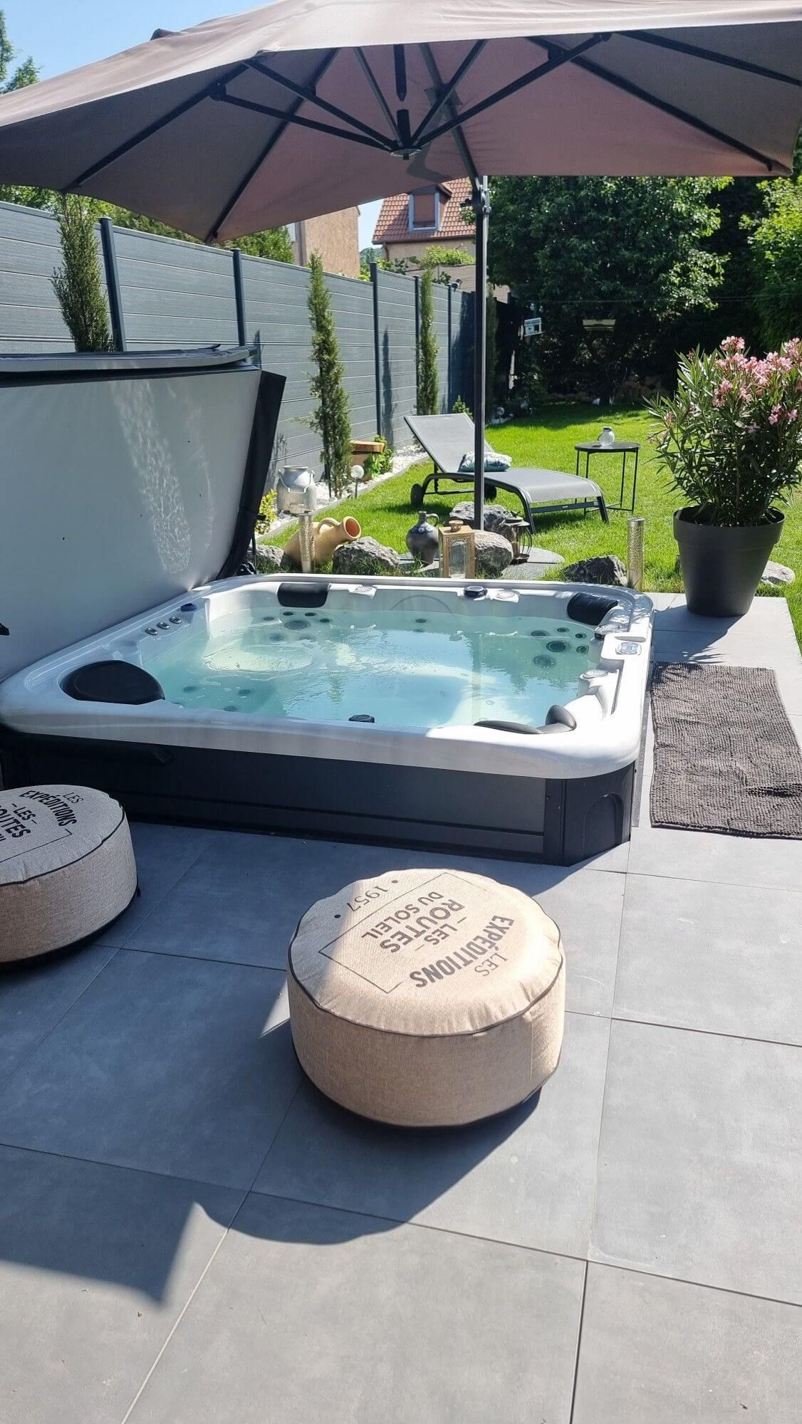 Un bain à remous est installé sous un parasol sur une terrasse.