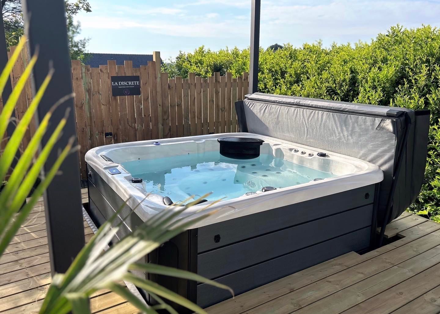 Un bain à remous est posé sur une terrasse en bois à côté d'une clôture.