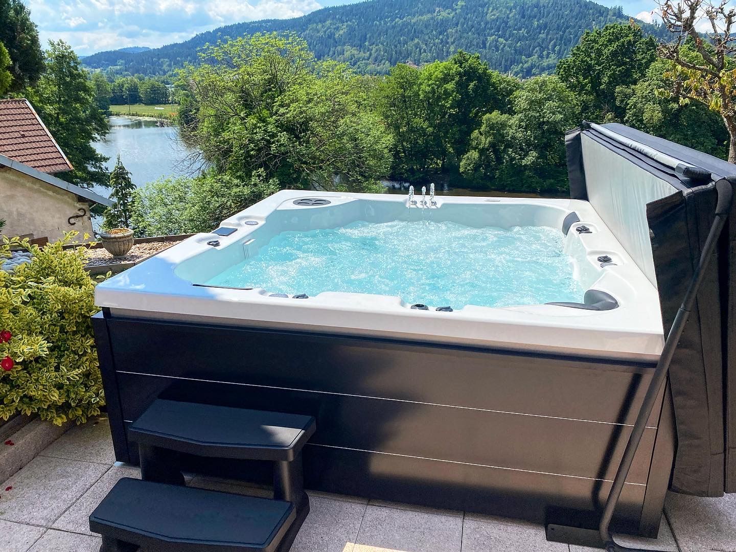 Un bain à remous est installé sur une terrasse avec vue sur un lac.