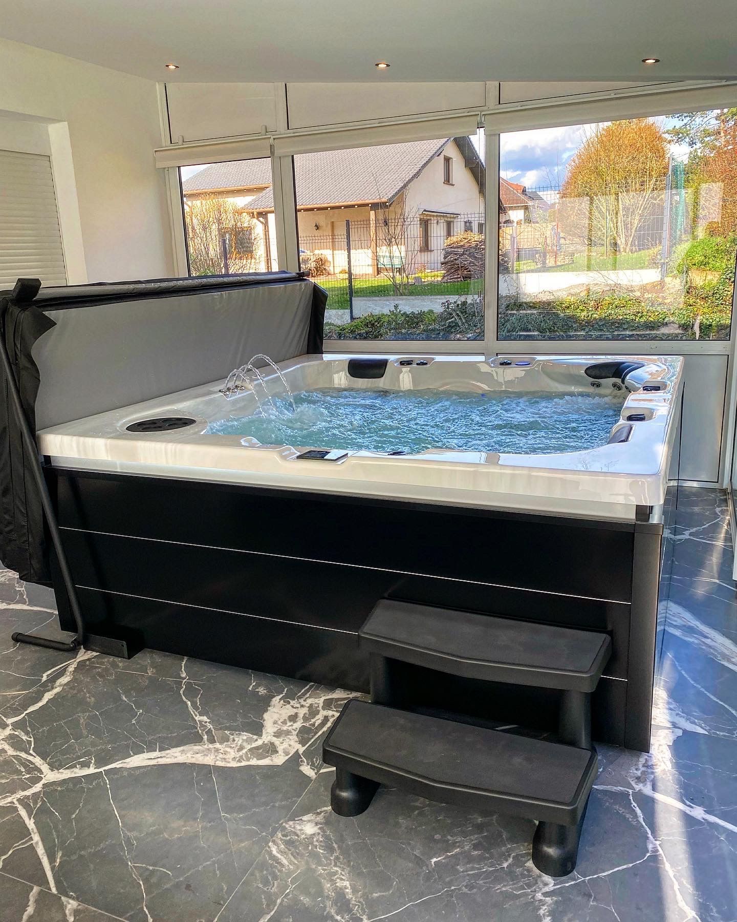 Un jacuzzi noir et blanc avec des escaliers dans une pièce.