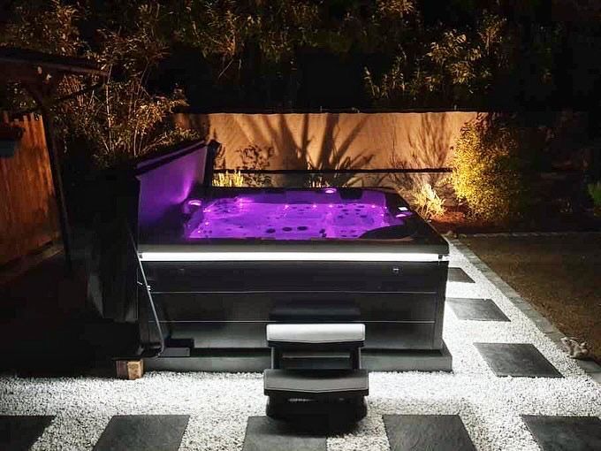 Un bain à remous est éclairé la nuit avec des lumières violettes.
