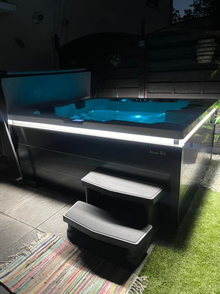 Un bain à remous avec des escaliers menant à celui-ci est éclairé la nuit.