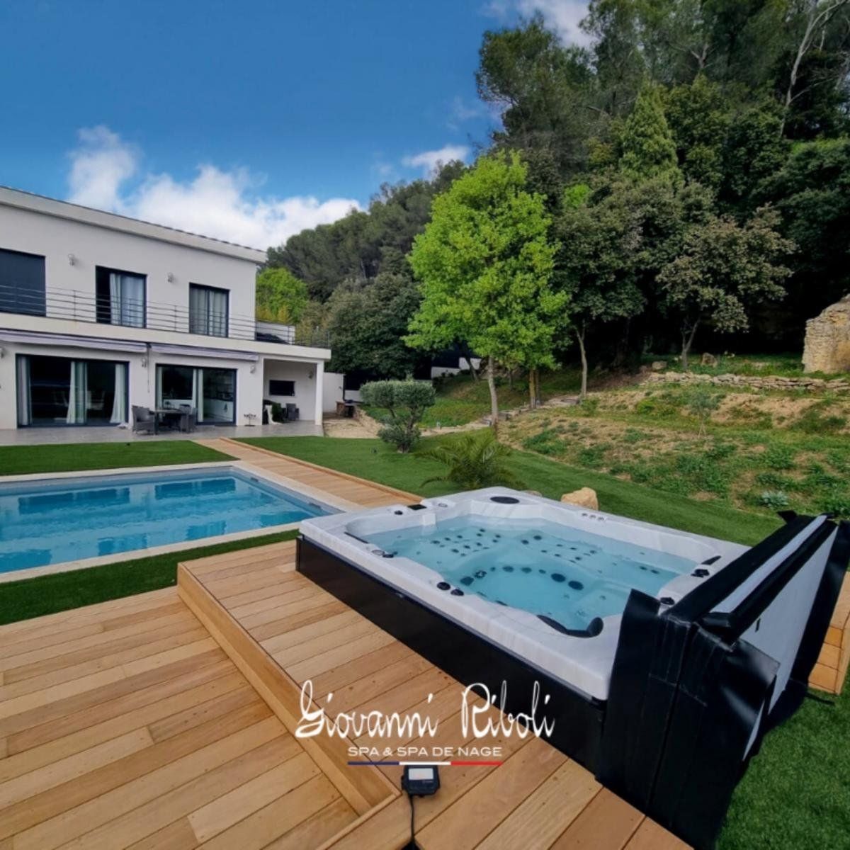 Un bain à remous est installé sur une terrasse en bois à côté d'une piscine