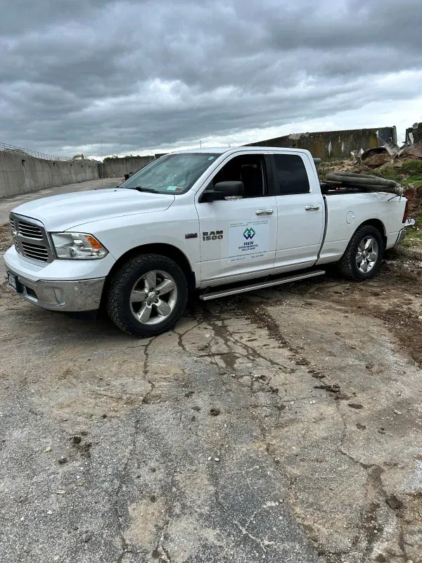 A white ram truck is parked on the side of the road.