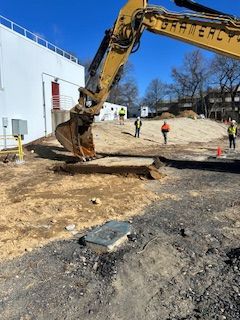 A large yellow excavator is digging a hole in the ground.