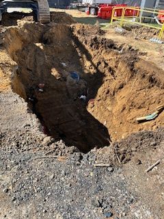 A large hole in the ground with a bulldozer in the background.