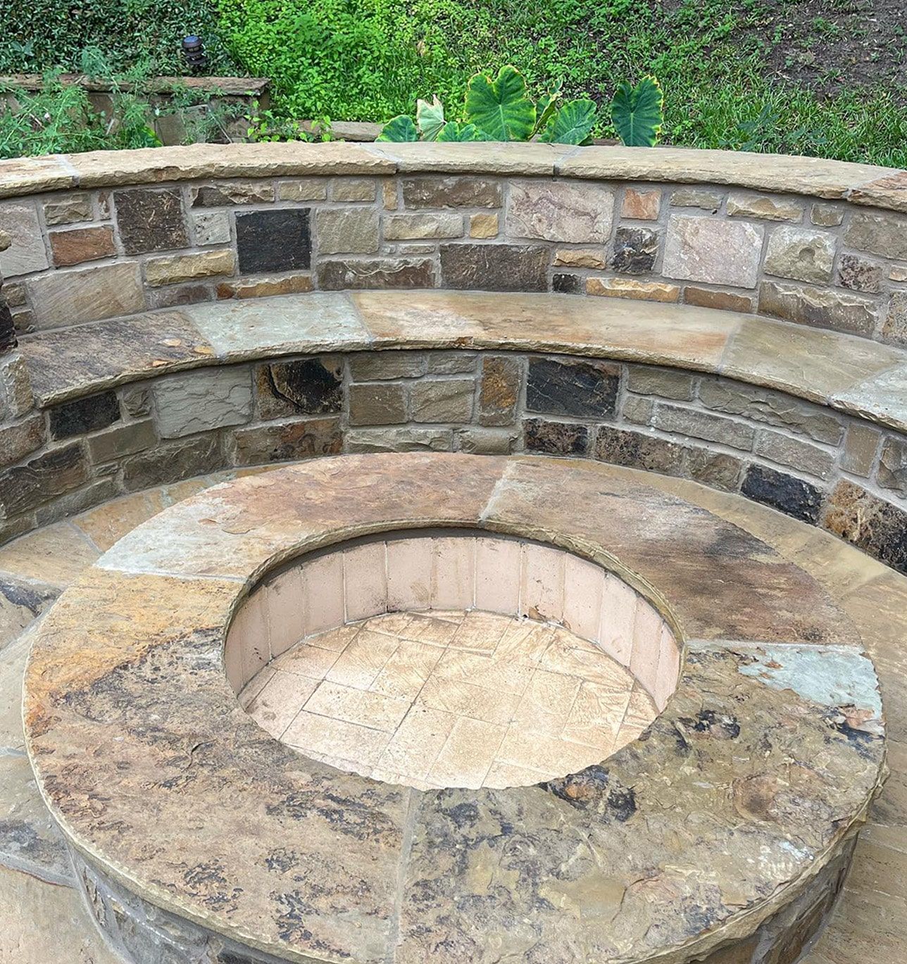 Stone fire pit with surrounding seating in a yard.