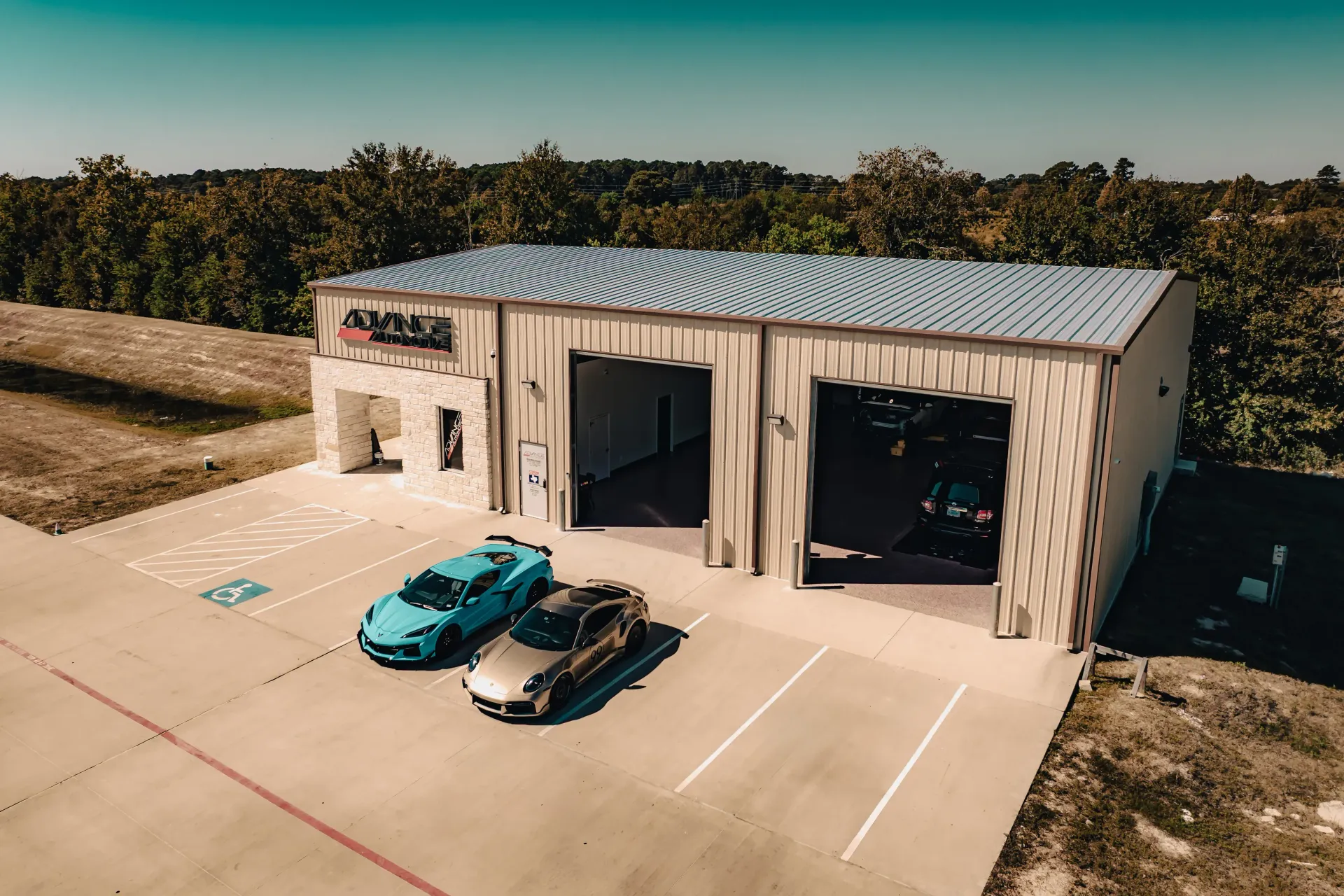 Exterior view of a car shop with two cars parked in front of open garage doors. | Advance Automotive