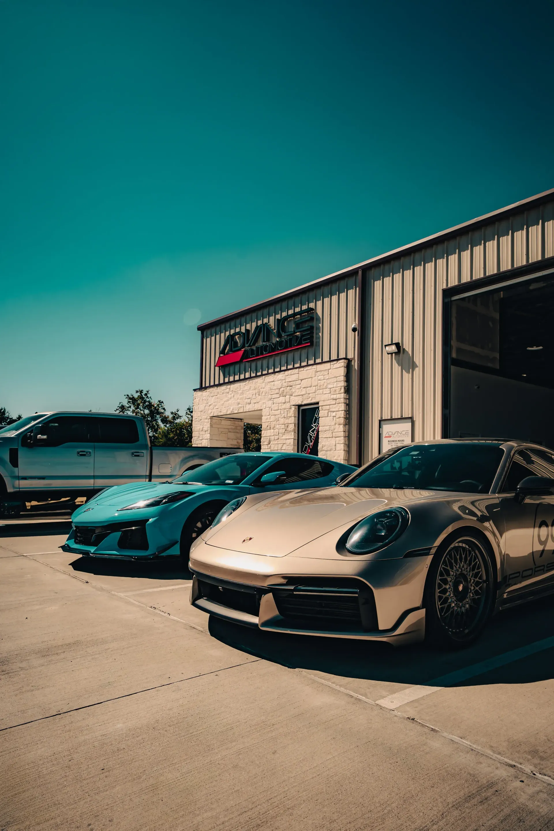 Three sports cars parked outside a building: blue, silver, and gold. Sunny day. | Advance Automotive