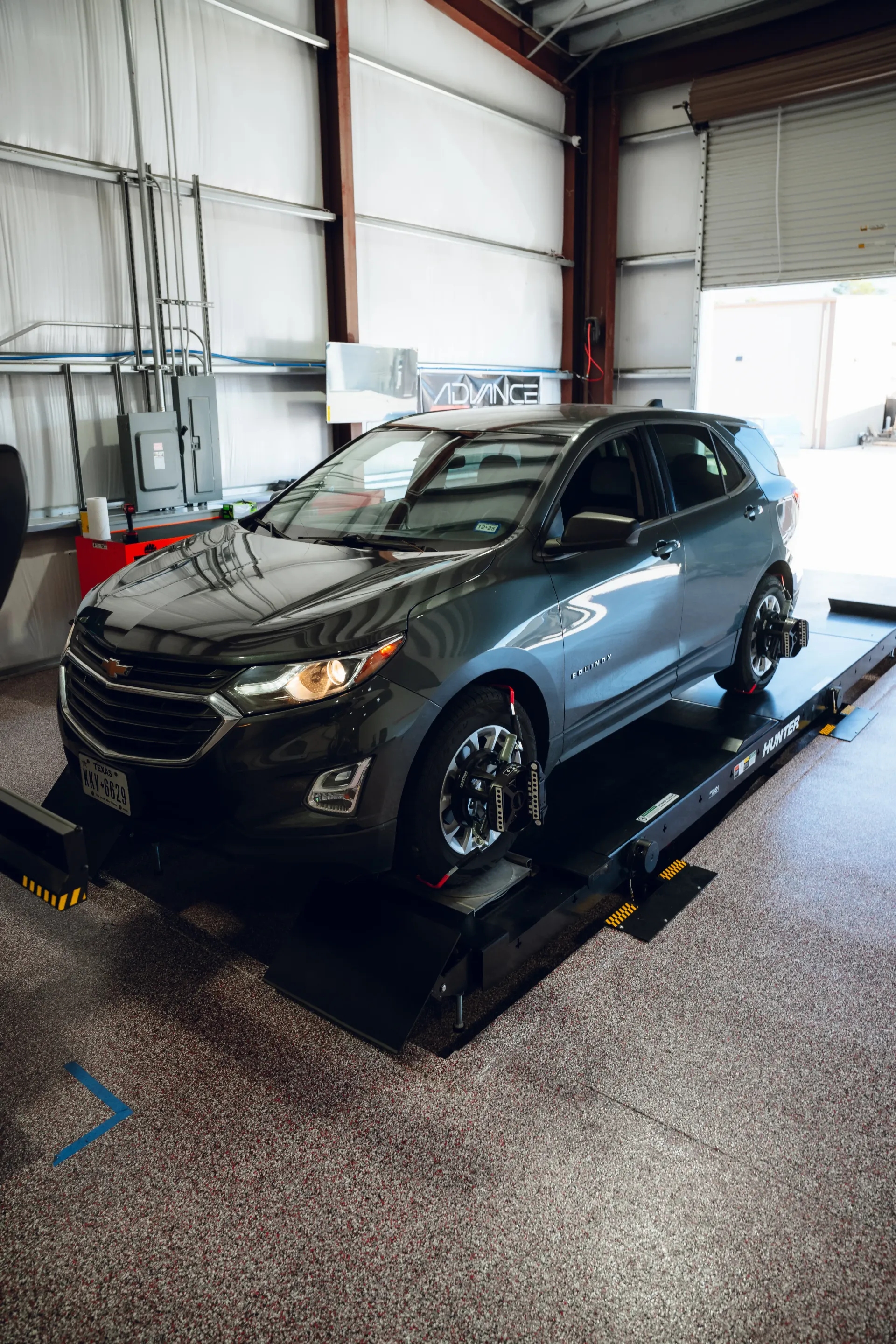 Gray SUV on an alignment lift in a garage. | Advance Automotive