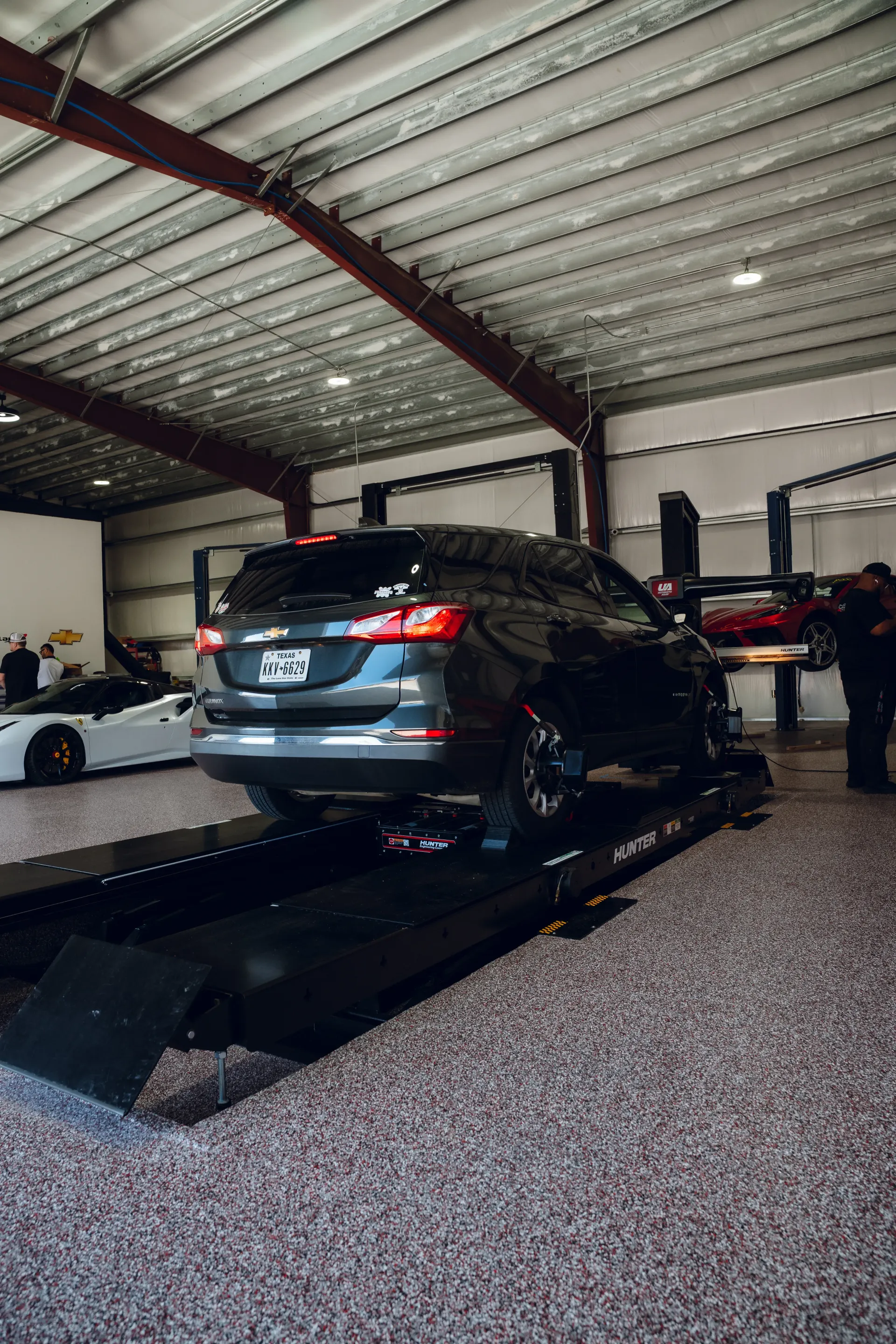 Dark SUV on a lift in a garage with a red car visible. | Advance Automotive