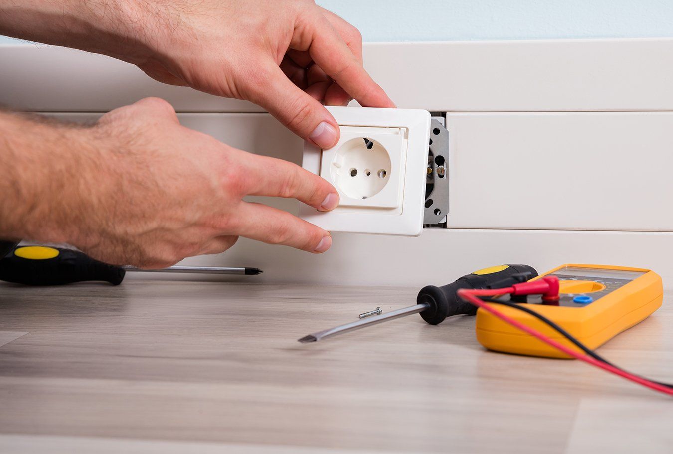 Close-up Of Person's Hand Installing Socket On Wall At Home
