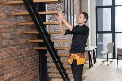 A worker is on a ladder, fixing the stairs.